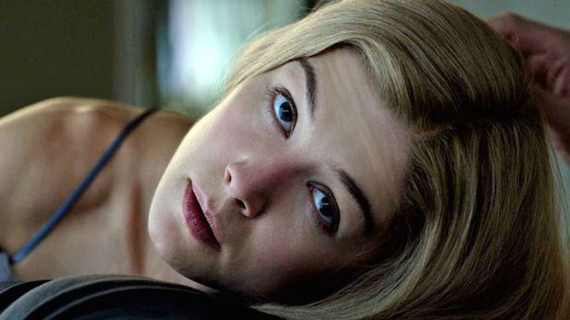 Rosamund Pike from 'Gone Girl' looking into the eyes of someone as their hand caresses her hair