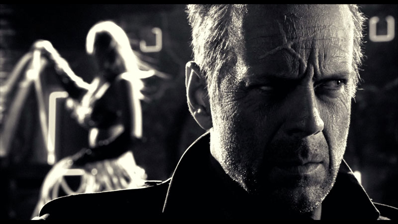 Bruce Willis from 'Sin City' looking away from his surrogate stripper daughter behind him played by Jessica Alba