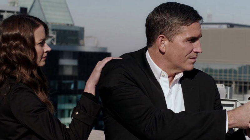 Two actors from 'Person of Interest' on CBS; one standing behind the other with her hand on his arm