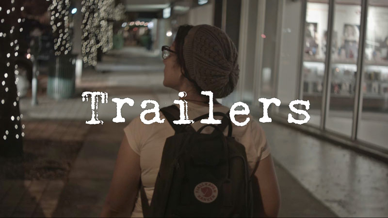 Trailers with a woman walking down a sidewalk at night